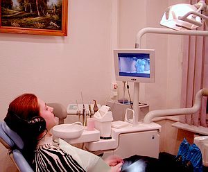 Cидя в зубоврачебном кресле клиники, пациент смотрит мультфильмы